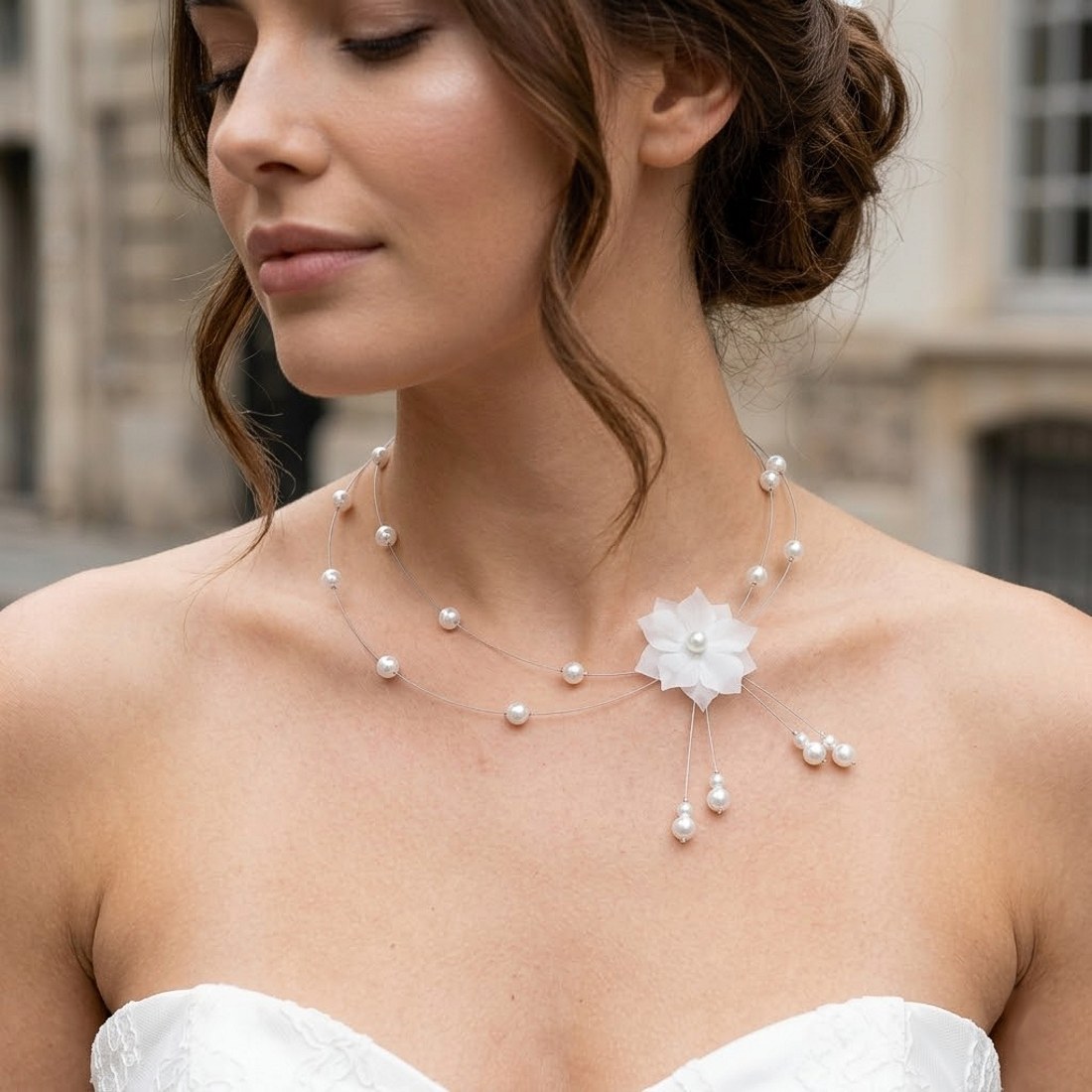 Collier de mariage fleur en soie blanche sur fil câblé argenté porté par une mariée.